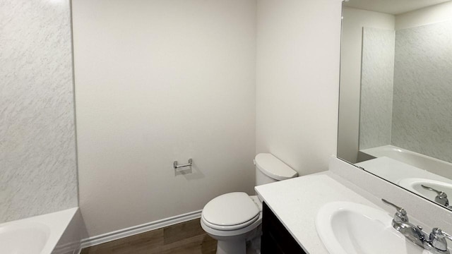 bathroom featuring wood-type flooring, vanity, toilet, and a bathtub