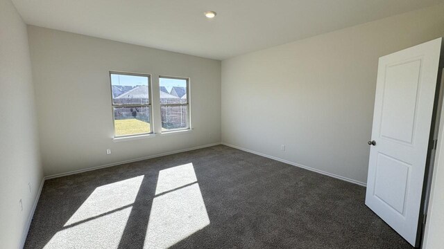 spare room featuring dark carpet