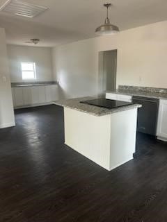 kitchen featuring dark wood-type flooring, a kitchen island, white cabinetry, and decorative light fixtures