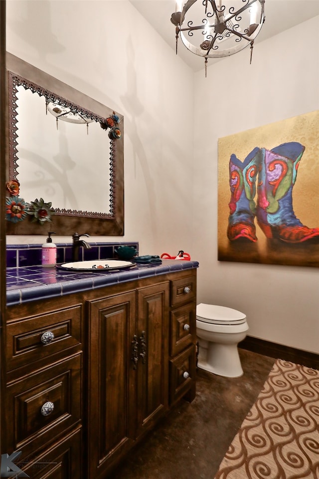 bathroom with an inviting chandelier, vanity, and toilet