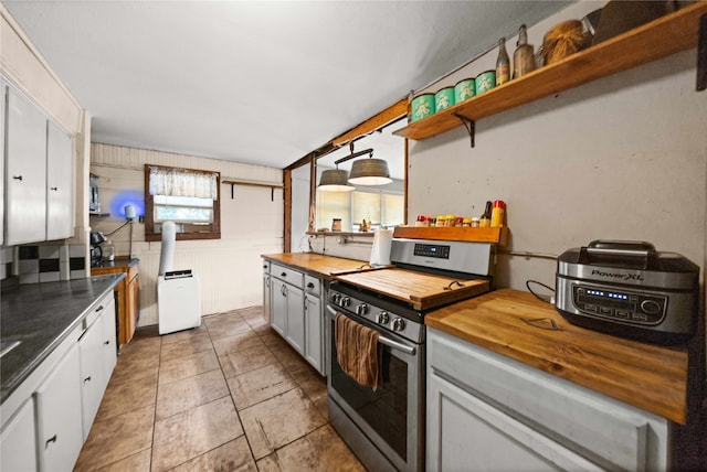 kitchen with stainless steel range oven, wooden walls, wooden counters, and white cabinets