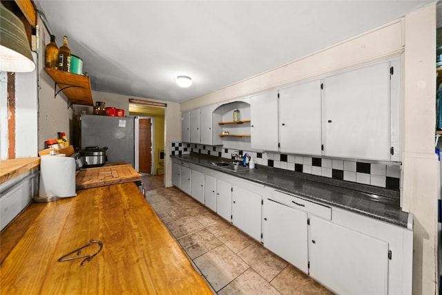 kitchen with white cabinetry, decorative backsplash, sink, and stainless steel refrigerator