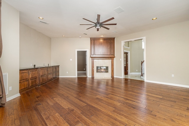 unfurnished living room featuring a fireplace, ceiling fan, and dark wood-type flooring