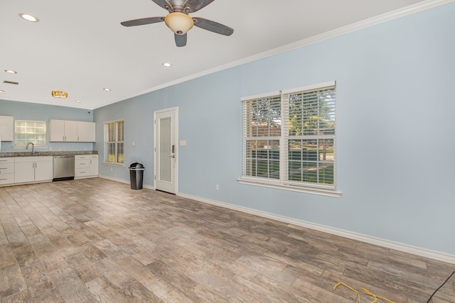 unfurnished living room with light wood-type flooring, a healthy amount of sunlight, ceiling fan, and sink