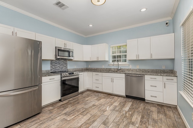 kitchen featuring stainless steel appliances, white cabinets, sink, and light wood-type flooring