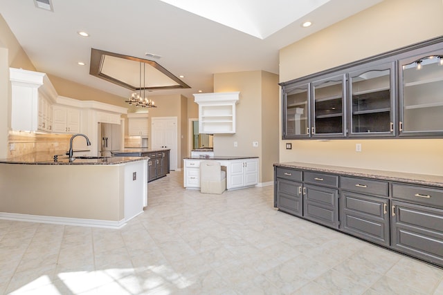 kitchen featuring gray cabinets, stainless steel fridge, decorative light fixtures, sink, and white cabinetry