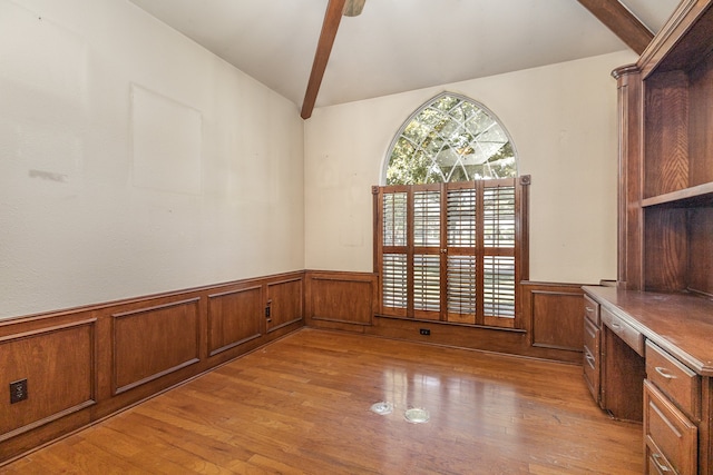 unfurnished dining area featuring light hardwood / wood-style flooring, built in desk, and lofted ceiling with beams