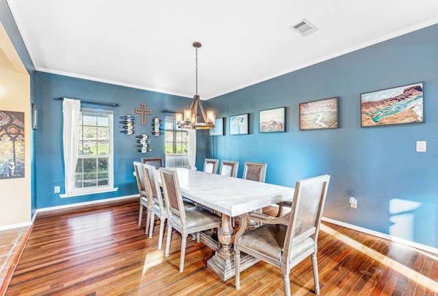 dining room featuring crown molding, hardwood / wood-style floors, and a notable chandelier