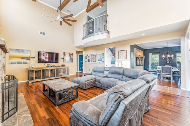 living room featuring ceiling fan with notable chandelier, dark wood-type flooring, beam ceiling, and a high ceiling