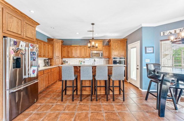 kitchen with a chandelier, a breakfast bar, stainless steel appliances, hanging light fixtures, and an island with sink