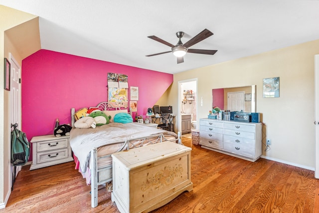 bedroom featuring ceiling fan, vaulted ceiling, ensuite bathroom, and wood-type flooring