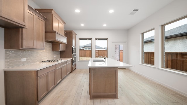 kitchen with an island with sink, stainless steel appliances, sink, and plenty of natural light