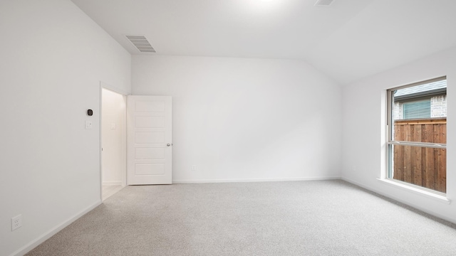 carpeted empty room featuring vaulted ceiling