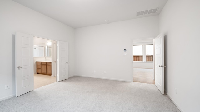 unfurnished bedroom with light carpet and ensuite bathroom