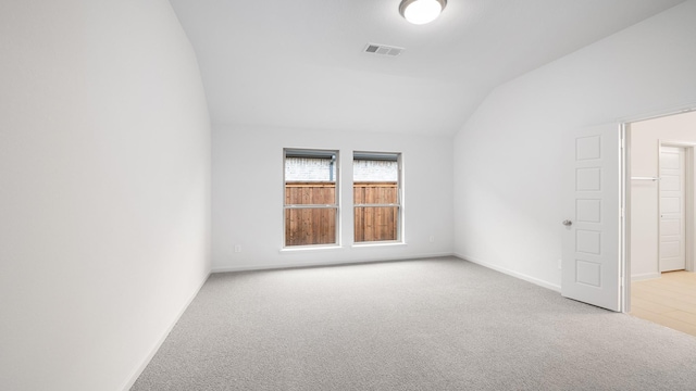 carpeted empty room featuring vaulted ceiling