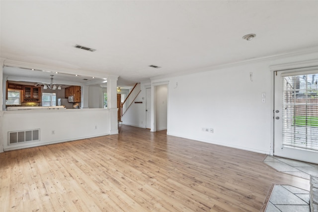 unfurnished living room featuring light hardwood / wood-style floors, crown molding, and a notable chandelier