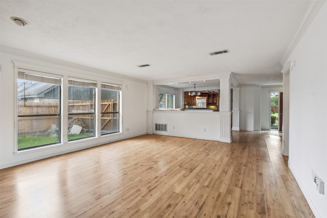 unfurnished living room featuring light wood-type flooring, plenty of natural light, and ornamental molding