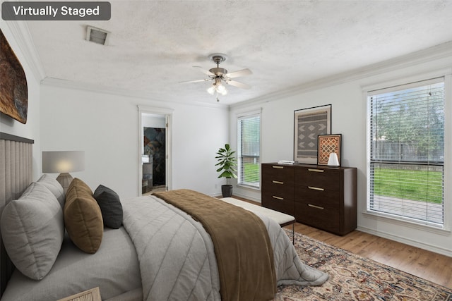 bedroom featuring ornamental molding, multiple windows, ceiling fan, and light hardwood / wood-style floors