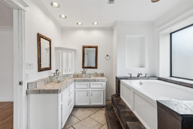 bathroom with tile patterned floors, vanity, crown molding, and a tub