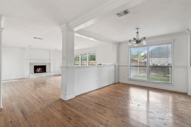 interior space with kitchen peninsula, light hardwood / wood-style flooring, decorative columns, an inviting chandelier, and crown molding