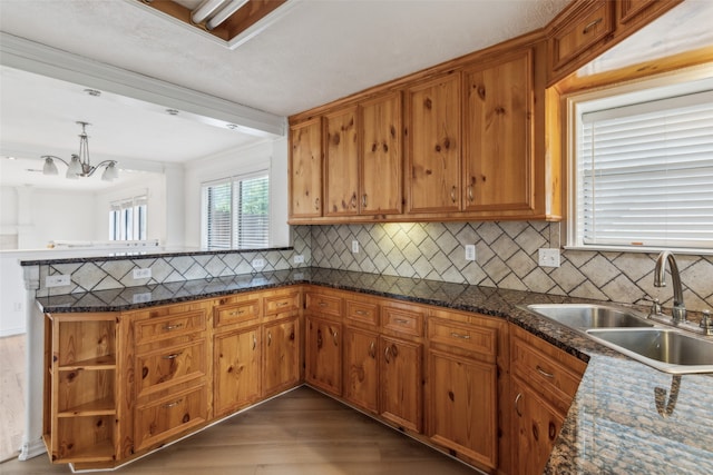 kitchen featuring sink, kitchen peninsula, tasteful backsplash, decorative light fixtures, and dark hardwood / wood-style floors