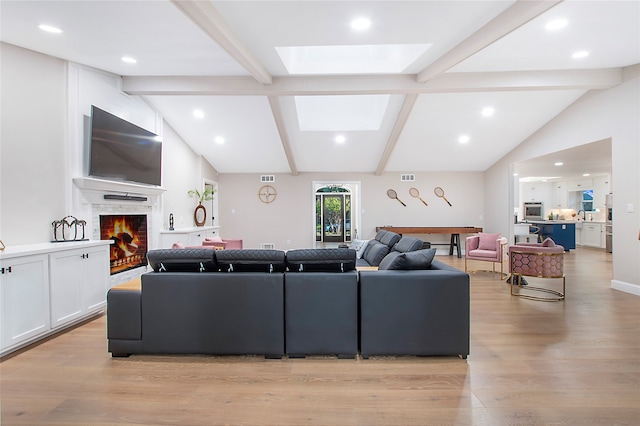 living room with vaulted ceiling with skylight, light wood-type flooring, and a fireplace