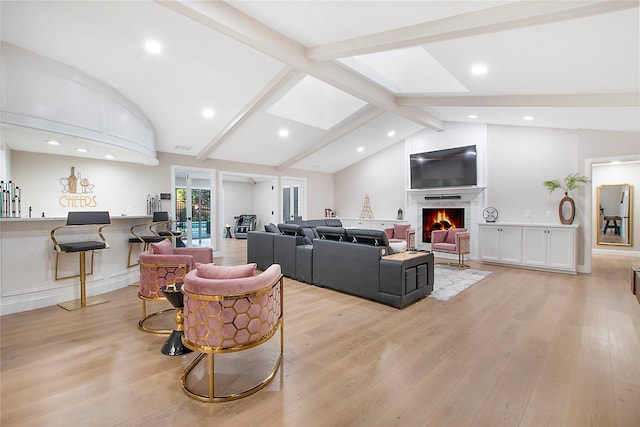 living room with lofted ceiling with skylight and light hardwood / wood-style flooring