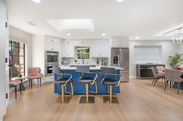 kitchen with a kitchen island, light hardwood / wood-style floors, stainless steel appliances, and white cabinets