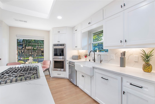 kitchen with white cabinets, appliances with stainless steel finishes, and a wealth of natural light