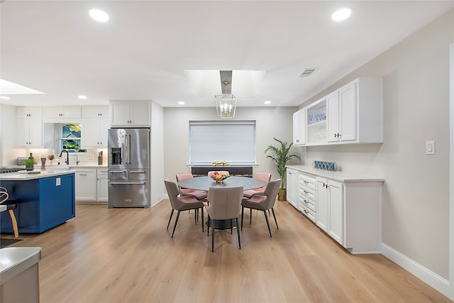 dining area featuring a skylight, sink, and light wood-type flooring