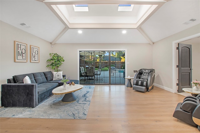 living room with light hardwood / wood-style floors and vaulted ceiling with skylight