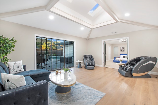 living room with hardwood / wood-style flooring and vaulted ceiling with skylight