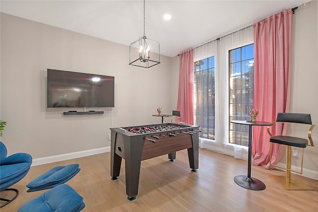 recreation room with light wood-type flooring, a notable chandelier, and a wealth of natural light