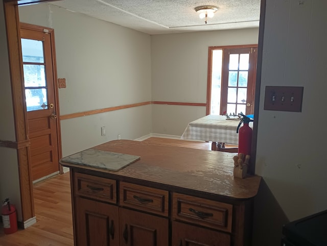 kitchen featuring dark stone countertops, light wood-type flooring, and dark brown cabinets