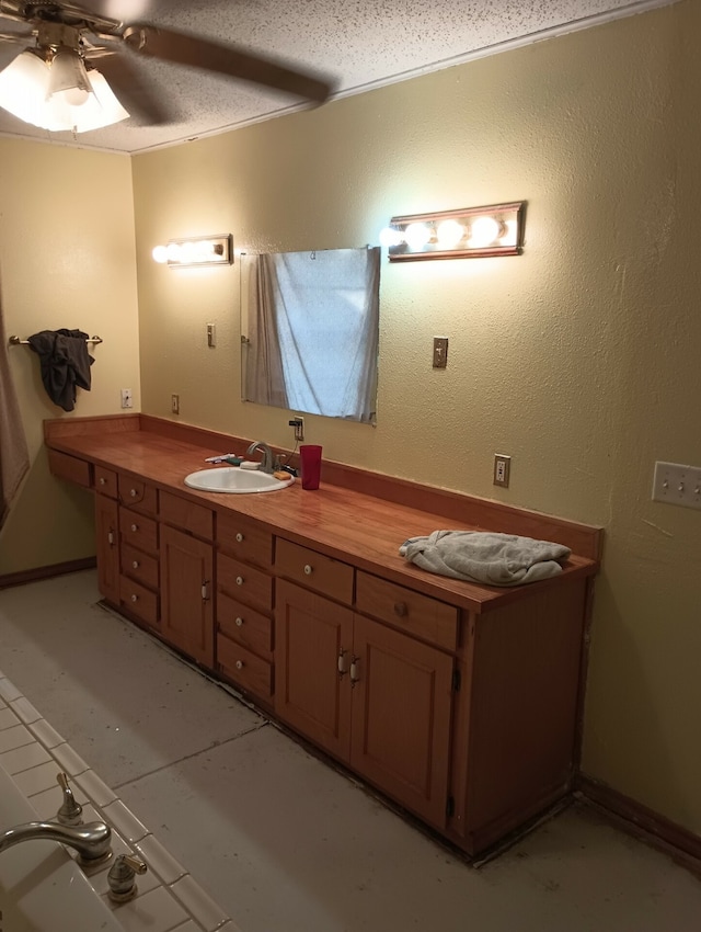 bathroom featuring ceiling fan, vanity, and a textured ceiling