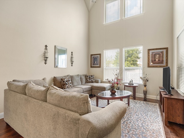 living room featuring a towering ceiling and dark wood-type flooring