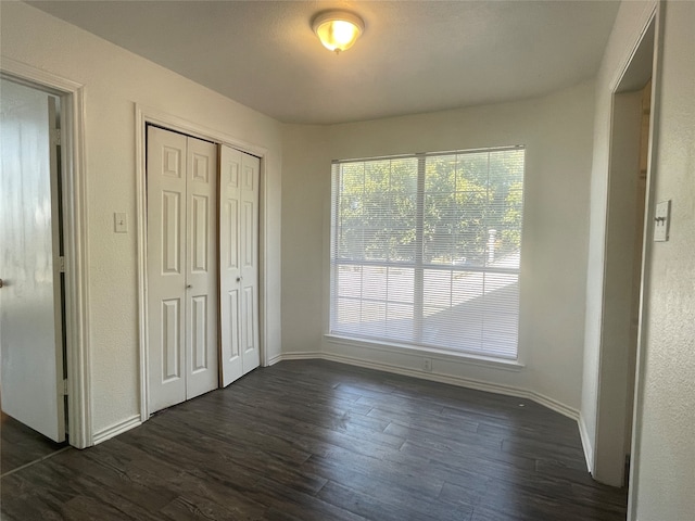 unfurnished bedroom with a closet and dark hardwood / wood-style flooring