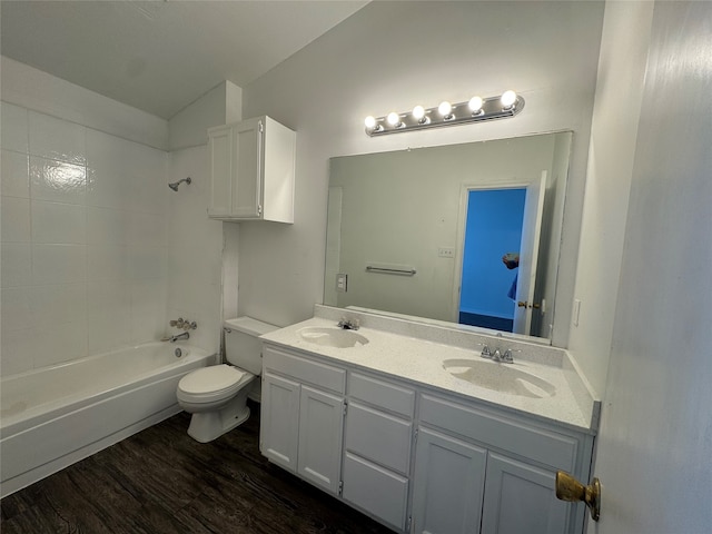 full bathroom featuring toilet, tiled shower / bath, hardwood / wood-style floors, vaulted ceiling, and vanity