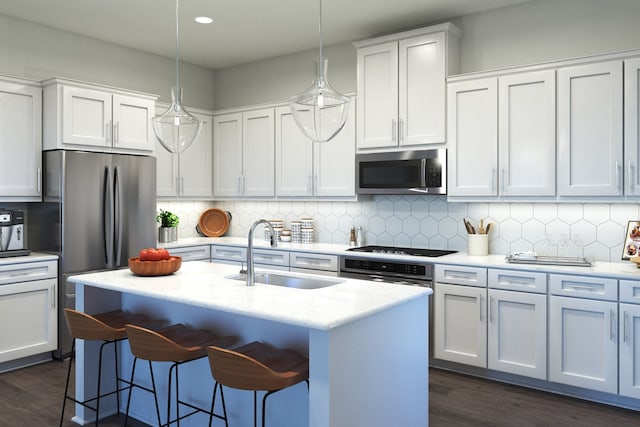 kitchen with appliances with stainless steel finishes, sink, a kitchen island with sink, and decorative light fixtures