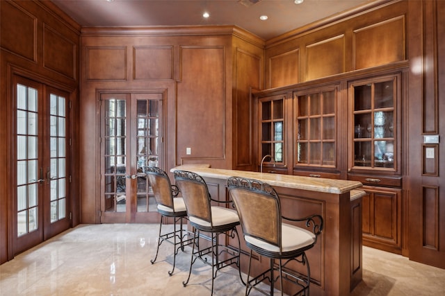 bar featuring french doors, light stone countertops, and ornamental molding