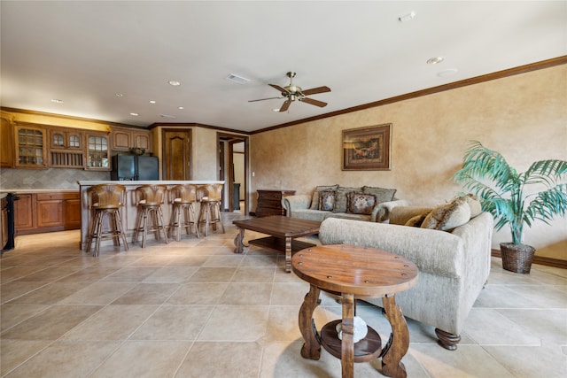 tiled living room with ornamental molding and ceiling fan