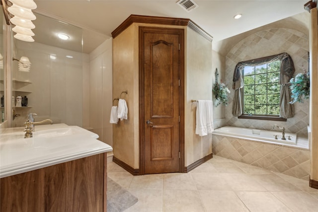 bathroom featuring tile patterned flooring, vanity, and tiled bath