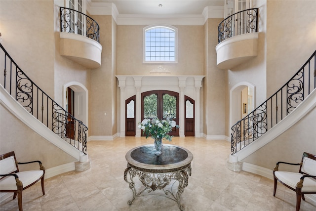 foyer featuring ornamental molding, a wealth of natural light, a towering ceiling, and french doors