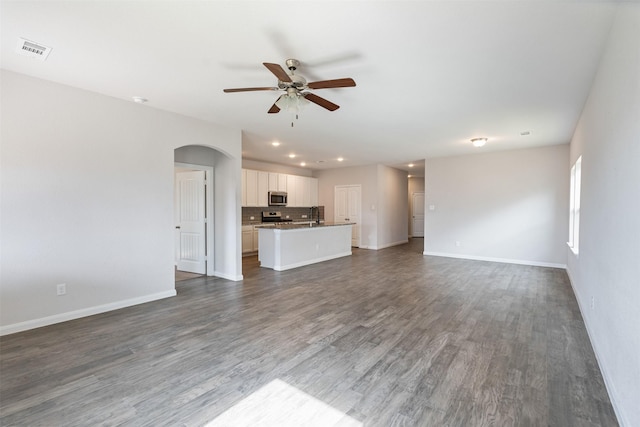 unfurnished living room featuring ceiling fan and dark hardwood / wood-style floors