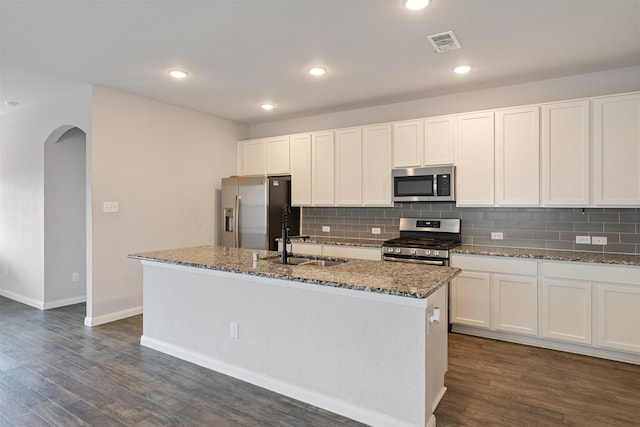 kitchen with white cabinetry, sink, dark stone counters, a kitchen island with sink, and appliances with stainless steel finishes