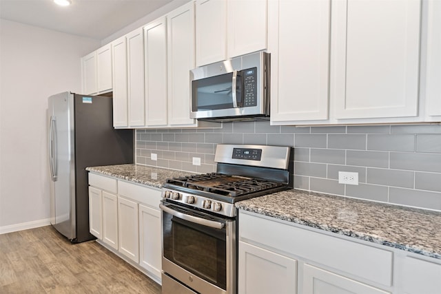 kitchen featuring light stone countertops, white cabinetry, stainless steel appliances, and light hardwood / wood-style flooring