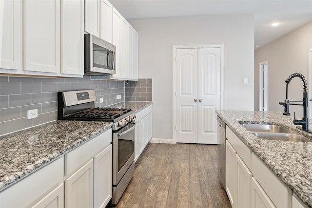 kitchen featuring white cabinets, appliances with stainless steel finishes, light stone countertops, and sink