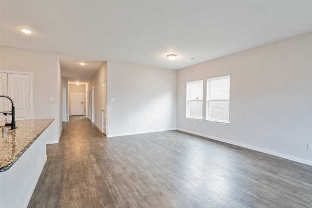 unfurnished living room with sink and dark wood-type flooring