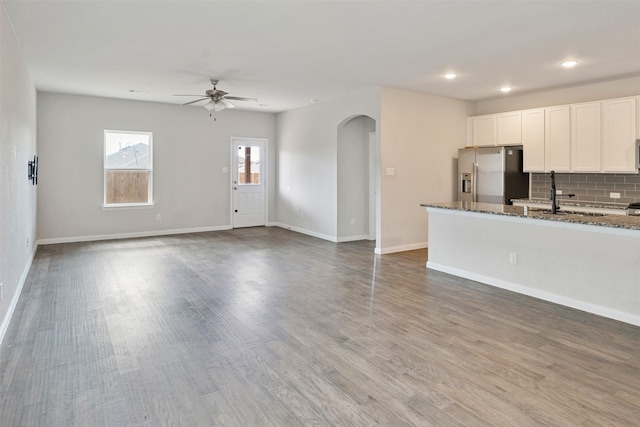 interior space with backsplash, white cabinets, ceiling fan, stainless steel fridge, and stone countertops