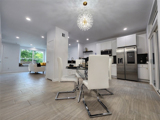 dining area featuring a notable chandelier and light wood-type flooring